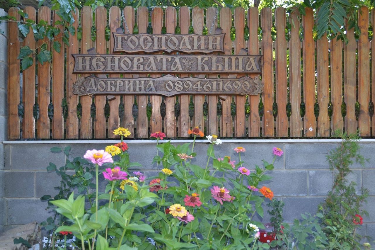 Табелата и цветята пред къщата